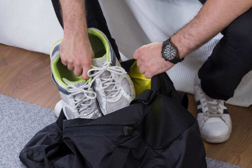 close shot of a man putting his shoes into a sports bag