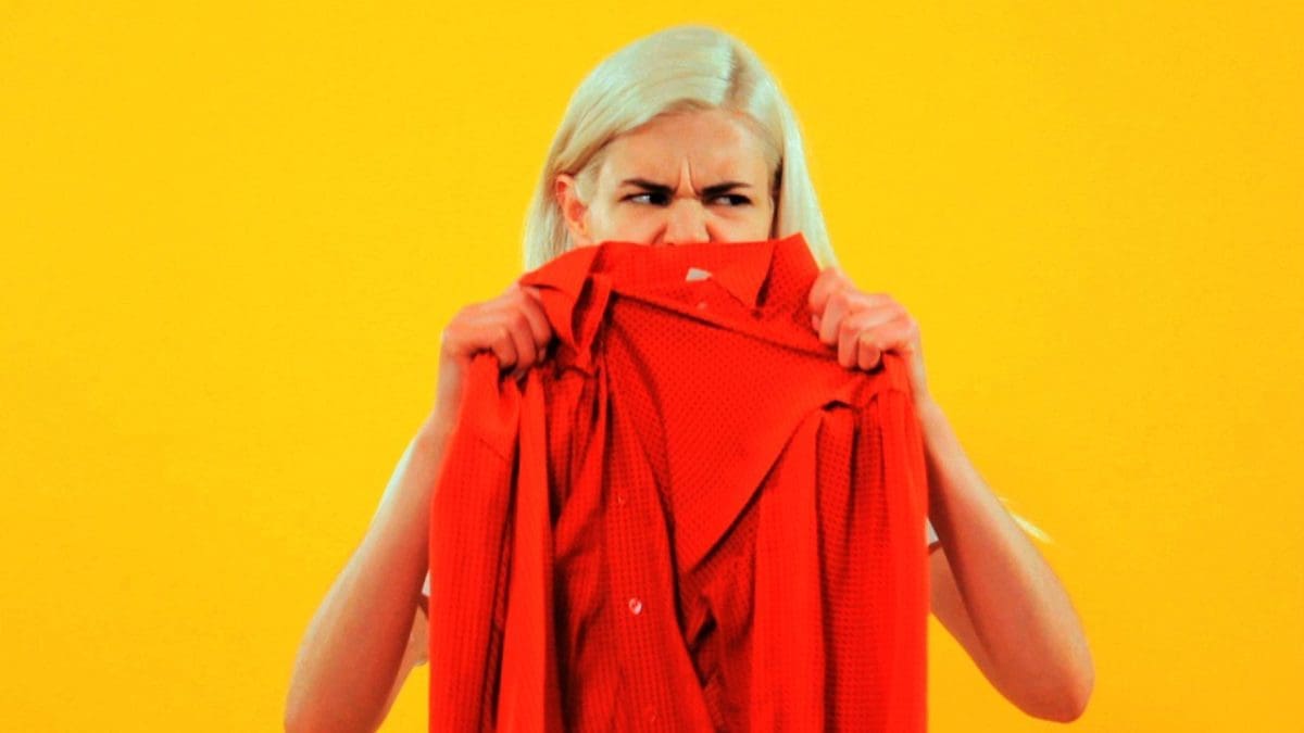 a woman sniffing smelly clothes.