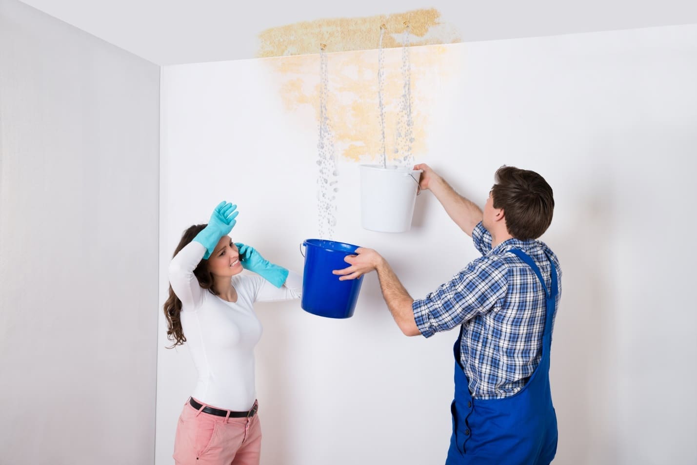 water leaking from ceiling and man putting bucket under the water and a woman in picture talking on the phone with a water damage removal company.