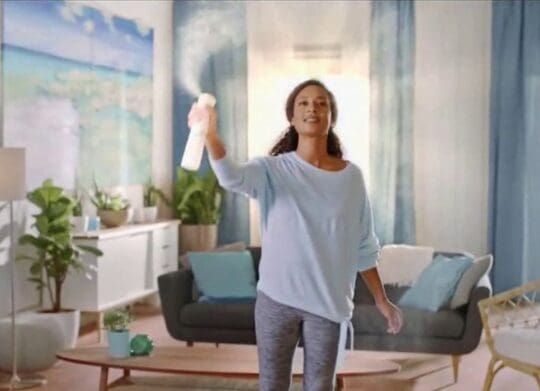 a woman spraying deodorizer in a room.