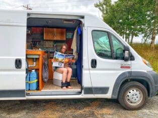 a woman sitting on the camper toilet and reading magazine.